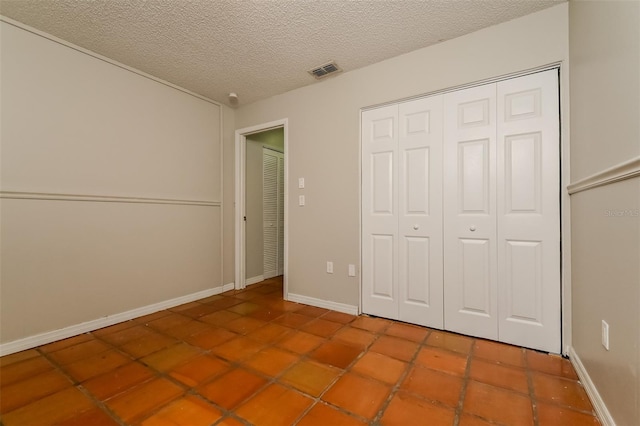 unfurnished bedroom with a textured ceiling, tile floors, and a closet