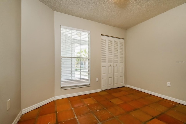 empty room featuring a textured ceiling and dark tile flooring