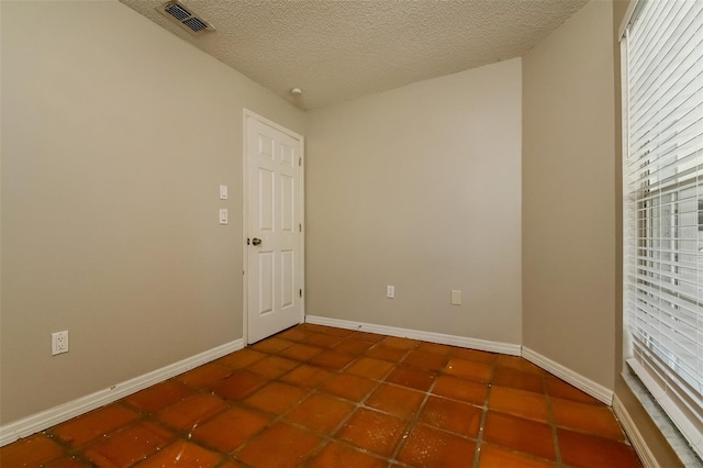 empty room with a textured ceiling and dark tile floors