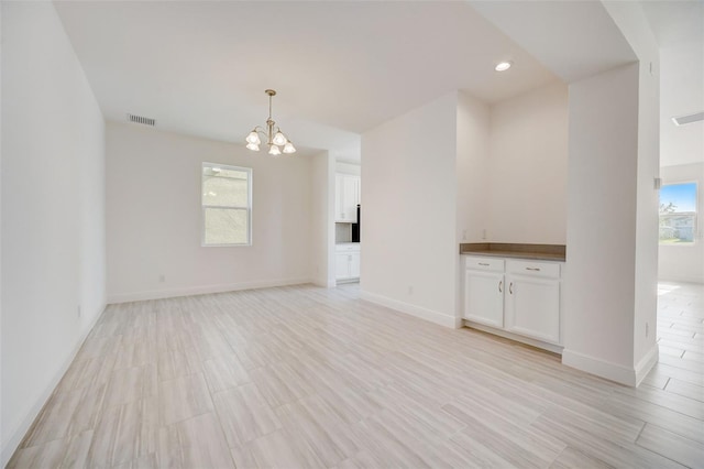 unfurnished living room with a wealth of natural light and an inviting chandelier