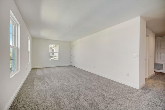 empty room featuring light colored carpet and a healthy amount of sunlight