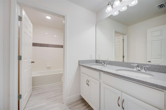 full bathroom with tiled shower / bath, toilet, and double sink vanity