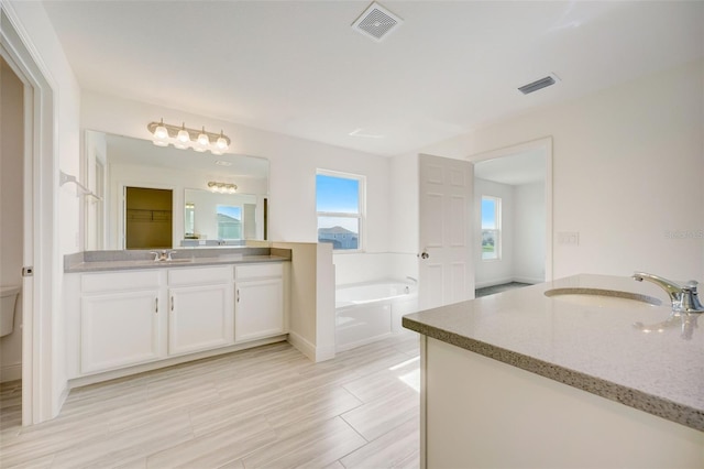 bathroom with tile floors, vanity, toilet, and a washtub