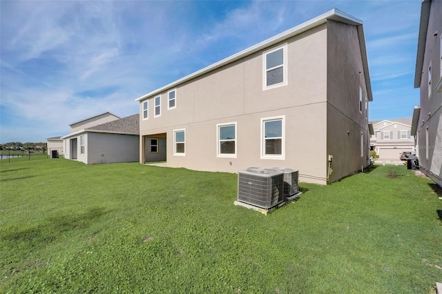 rear view of house with a yard and central AC