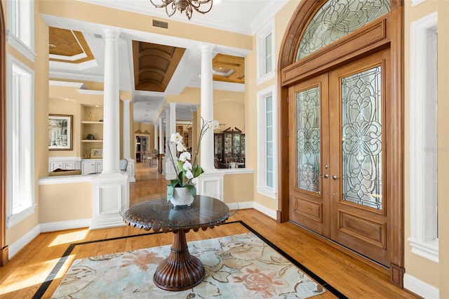 entryway featuring french doors, decorative columns, coffered ceiling, light wood-type flooring, and ornamental molding