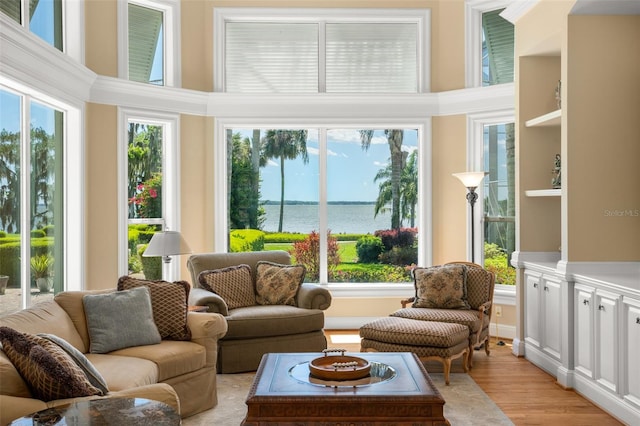 living room featuring built in shelves, plenty of natural light, a towering ceiling, and a water view