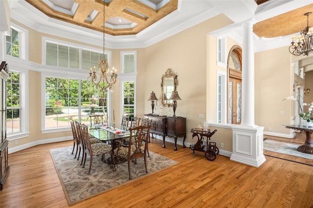 dining area with light hardwood / wood-style floors, decorative columns, coffered ceiling, and an inviting chandelier