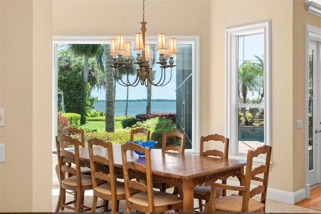 dining area with light hardwood / wood-style floors, a water view, and an inviting chandelier