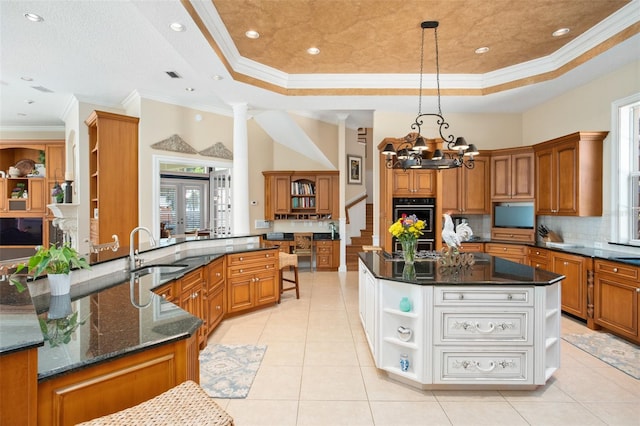 kitchen featuring plenty of natural light, sink, a tray ceiling, and an island with sink