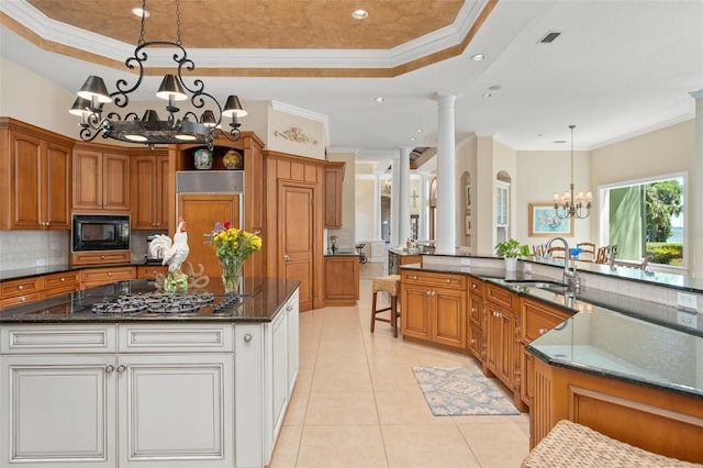 kitchen featuring sink, decorative columns, a tray ceiling, and built in appliances