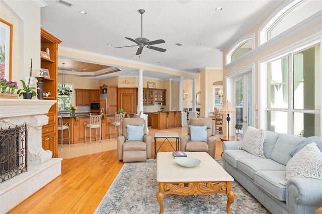 living room with a wealth of natural light, ceiling fan, light hardwood / wood-style floors, and a premium fireplace