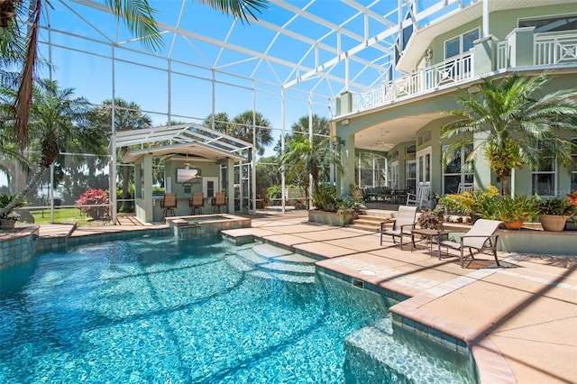 view of swimming pool with ceiling fan, an in ground hot tub, glass enclosure, and a patio