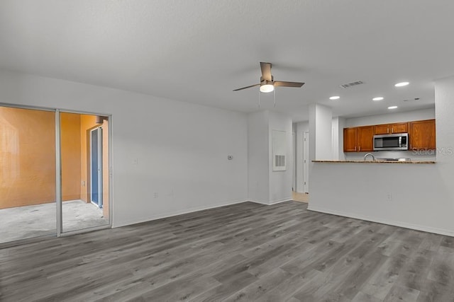 unfurnished living room featuring ceiling fan and light wood-type flooring