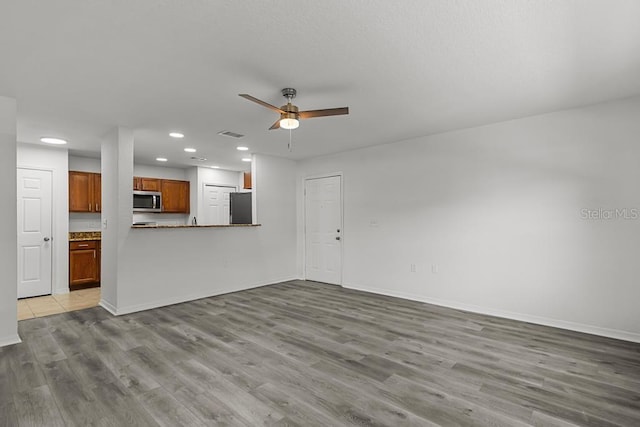 unfurnished living room featuring ceiling fan and light wood-type flooring