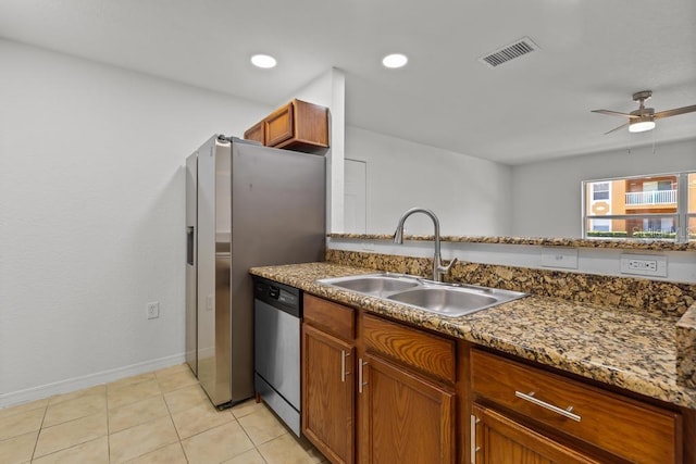 kitchen with stainless steel appliances, ceiling fan, dark stone counters, sink, and light tile floors