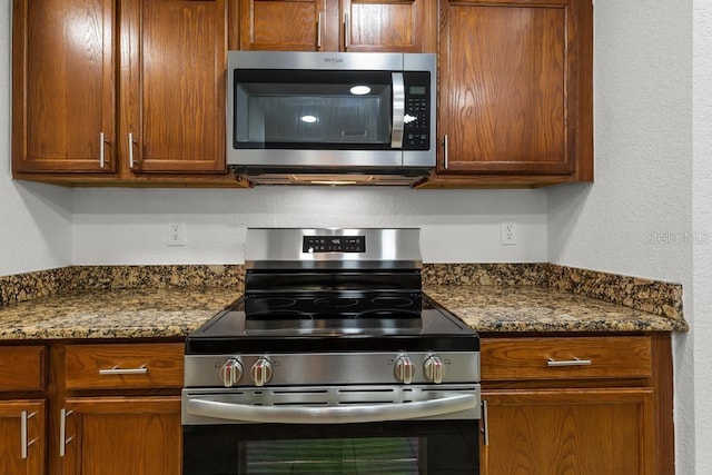 kitchen featuring stainless steel appliances and dark stone counters