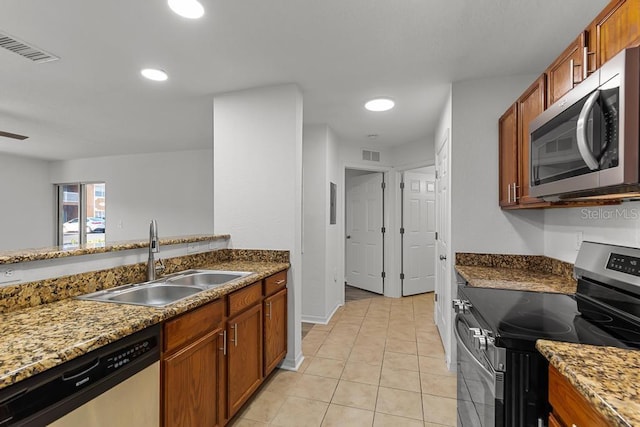 kitchen with sink, dark stone countertops, light tile floors, and stainless steel appliances