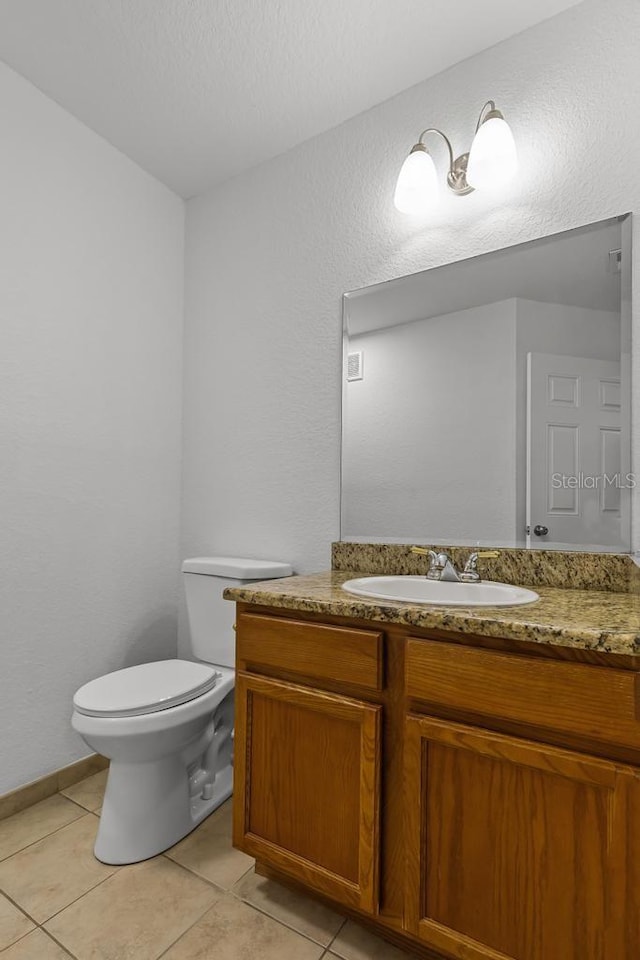 bathroom featuring tile flooring, vanity, and toilet