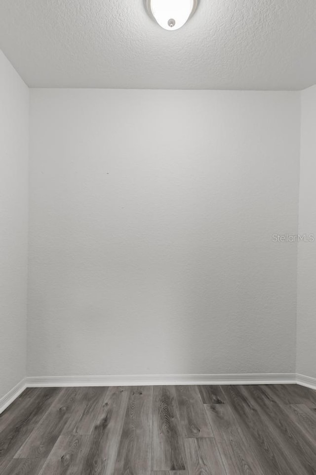 spare room featuring dark hardwood / wood-style floors and a textured ceiling