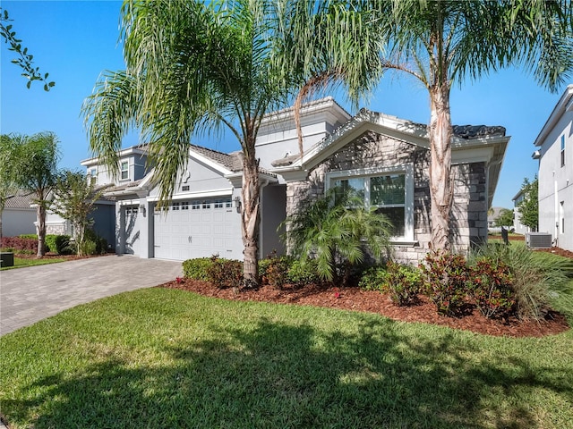 view of front of house featuring a garage, a front lawn, and central air condition unit