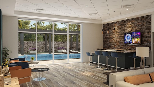 living room with bar area, wood-type flooring, and a raised ceiling