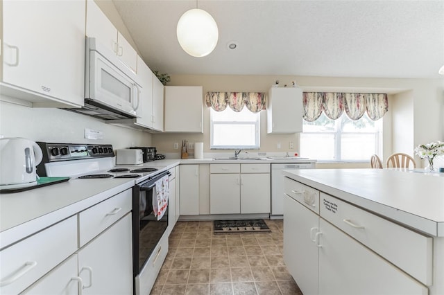 kitchen featuring sink, white appliances, light tile flooring, white cabinetry, and decorative light fixtures