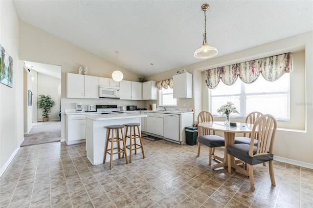 kitchen featuring white cabinets, white appliances, light tile flooring, a kitchen bar, and vaulted ceiling