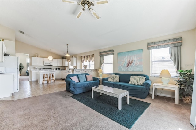 living room featuring a healthy amount of sunlight, ceiling fan, vaulted ceiling, and light colored carpet