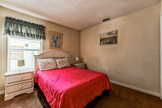 bedroom with a textured ceiling and dark carpet