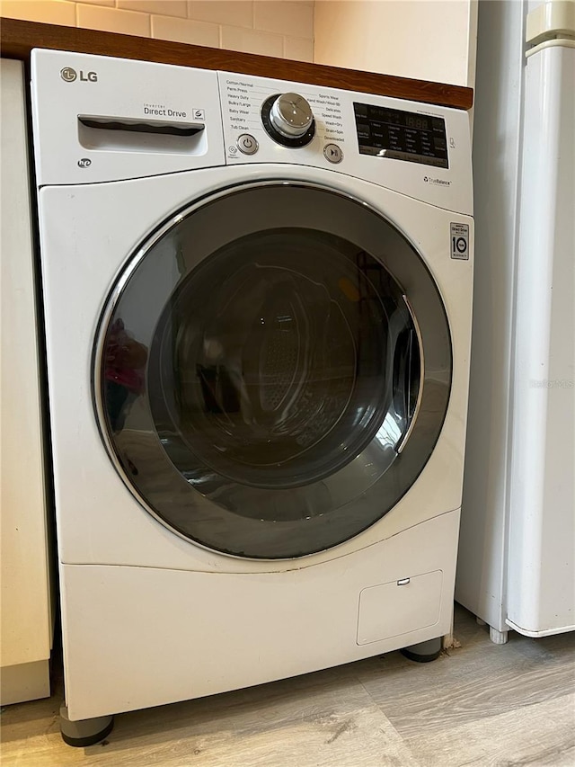 clothes washing area with light hardwood / wood-style floors and washer / clothes dryer