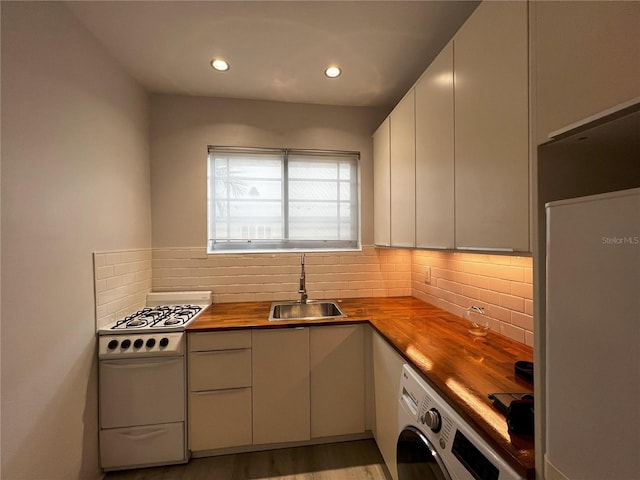 kitchen with washer / clothes dryer, sink, light hardwood / wood-style floors, butcher block counters, and range with gas stovetop