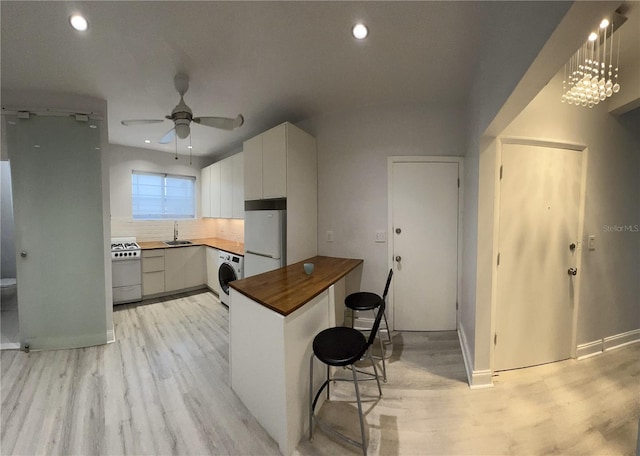 kitchen with white appliances, washer / dryer, white cabinets, sink, and light wood-type flooring