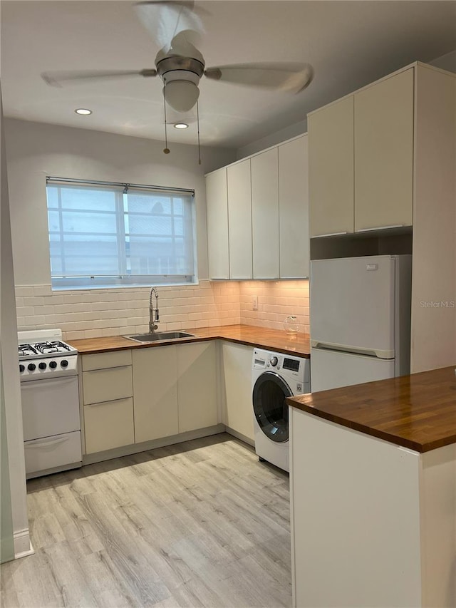 kitchen featuring butcher block counters, white appliances, light hardwood / wood-style floors, washer / clothes dryer, and sink