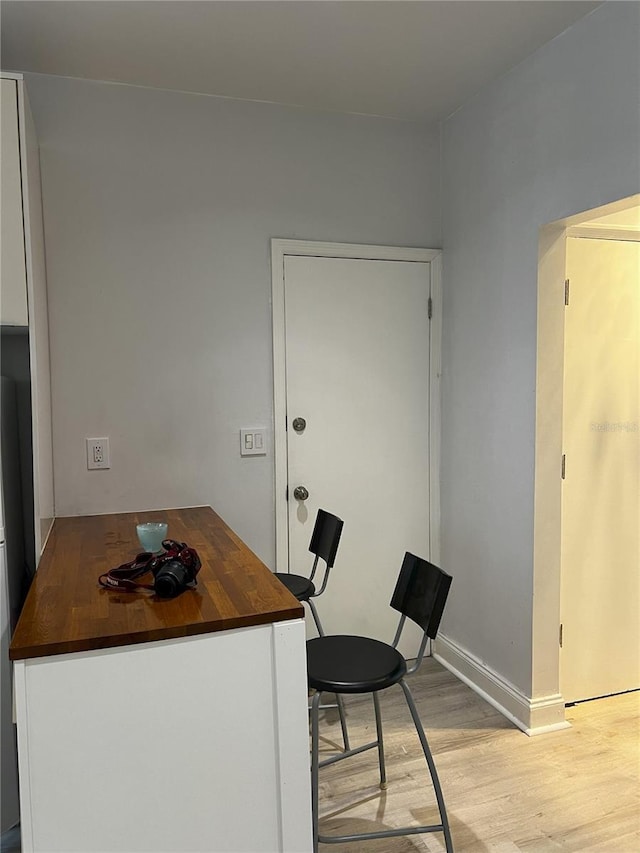 kitchen featuring white cabinets, a breakfast bar area, light wood-type flooring, and butcher block counters