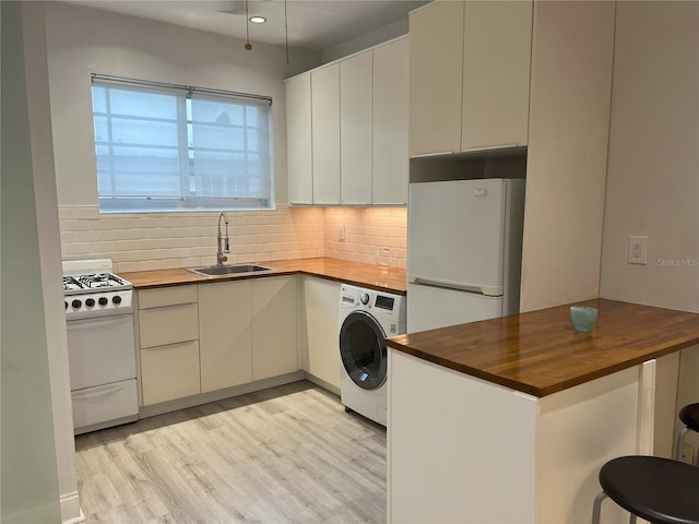 kitchen featuring butcher block counters, white appliances, light hardwood / wood-style floors, washer / clothes dryer, and sink