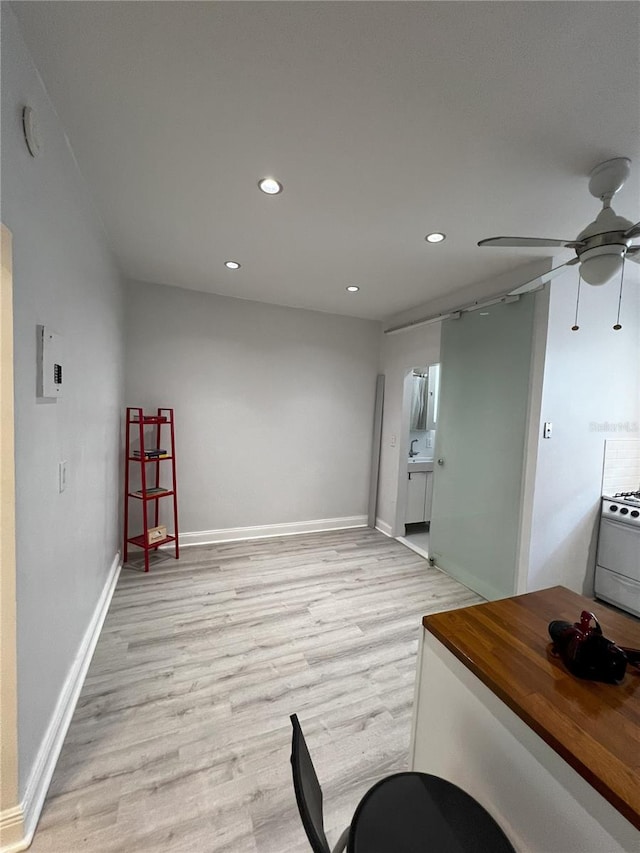 interior space featuring ceiling fan, light hardwood / wood-style floors, and white range with gas cooktop