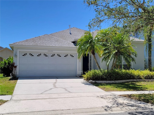 view of front of home with driveway, stucco siding, an attached garage, and roof with shingles