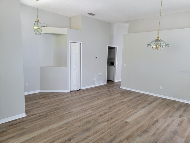 empty room featuring washer / dryer, visible vents, baseboards, and wood finished floors