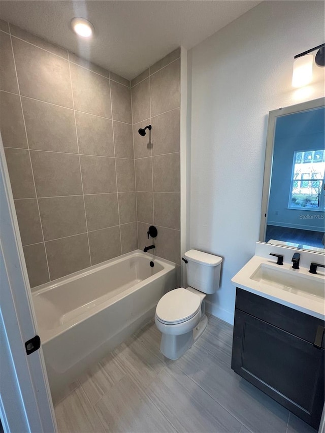 full bathroom with toilet, tiled shower / bath, and vanity