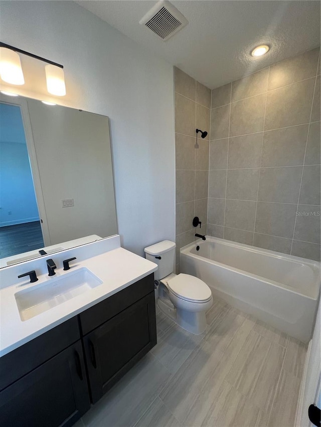 full bathroom featuring toilet, tiled shower / bath combo, and vanity