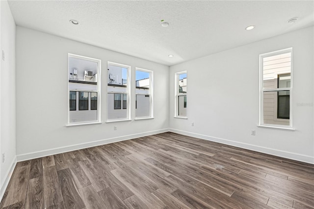 empty room with a textured ceiling and dark hardwood / wood-style flooring