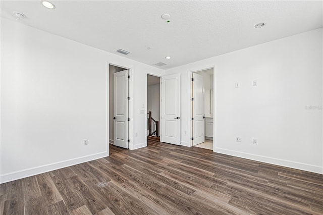 unfurnished bedroom with dark hardwood / wood-style flooring and connected bathroom