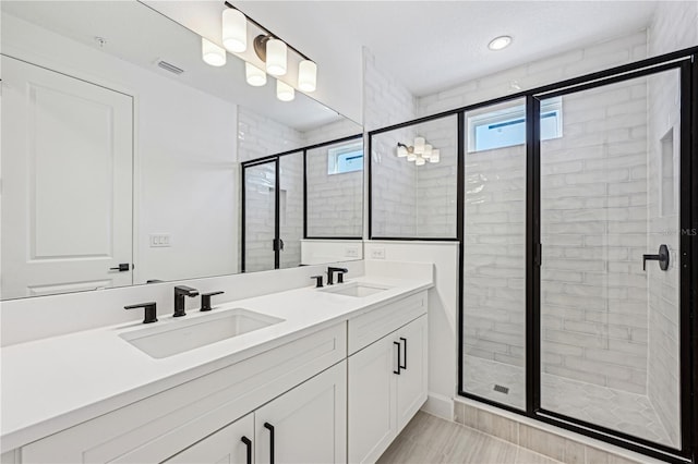 bathroom with a shower with shower door and vanity