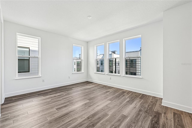 unfurnished room with hardwood / wood-style flooring and a textured ceiling