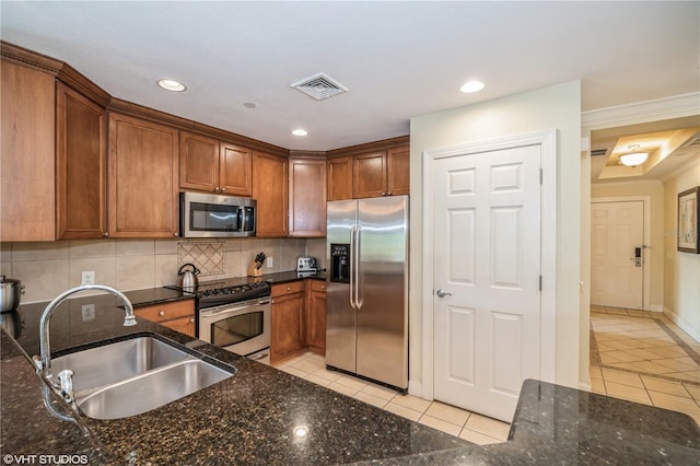 kitchen featuring backsplash, stainless steel appliances, dark stone counters, sink, and light tile floors