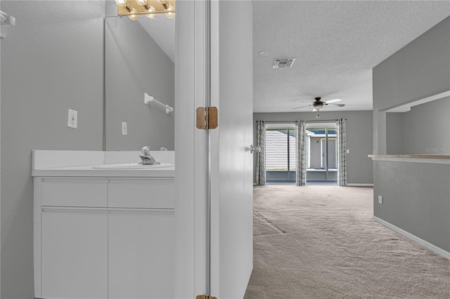 corridor featuring a textured ceiling, sink, light carpet, and a chandelier