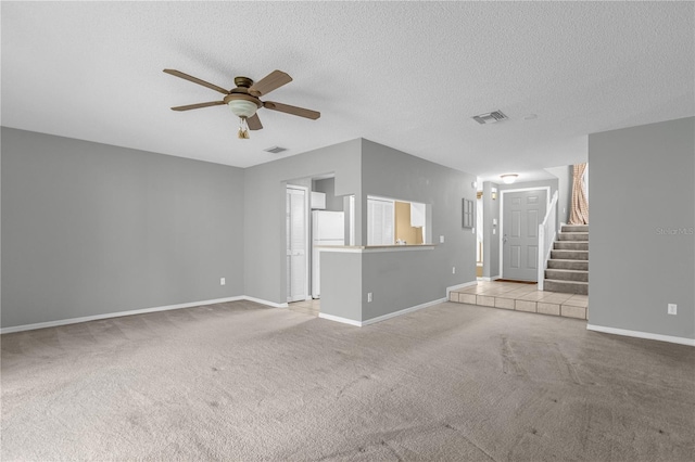 unfurnished living room with a textured ceiling, stairway, carpet, and visible vents