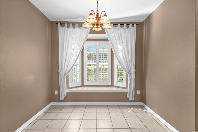 spare room with a notable chandelier and light tile flooring