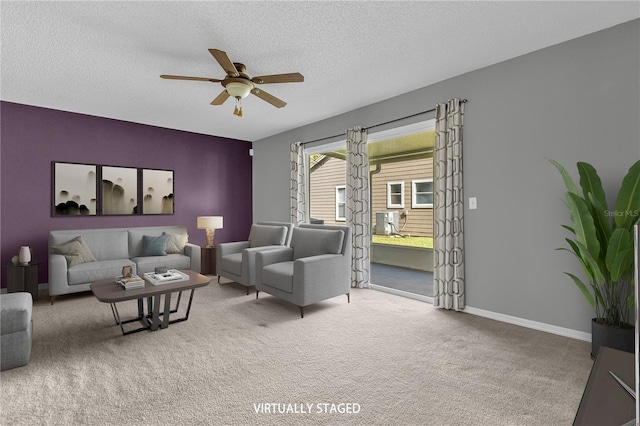 living area featuring carpet floors, ceiling fan, baseboards, and a textured ceiling