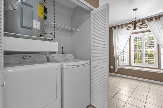 clothes washing area with washing machine and clothes dryer, light tile patterned floors, an inviting chandelier, electric water heater, and laundry area